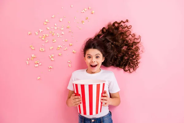 Top view above high angle flat lay flatlay lie concept portrait of her she nice lovely funny cheerful wavy-haired girl eating corn having fun watching movie isolated on pink pastel color background