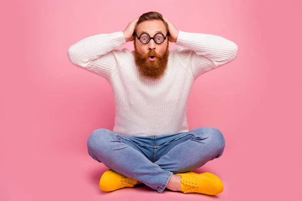 Full size photo astonished guy sit floor legs crossed look eyewear eyeglasses wonderful discount novelty touch head hands scream wear knitted sweater gumshoes isolated pastel color background — Stock Photo, Image