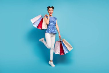 Full length photo of pretty lady carry many packs spree addicted shopaholic rejoicing shopping center wear dotted blouse white pants footwear isolated blue color background clipart
