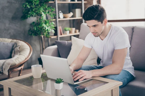 Portrait of his he nice attractive focused skilled experienced guy sitting on divan typing letter email report working remotely at modern industrial loft interior style living-room indoors — Stock Photo, Image