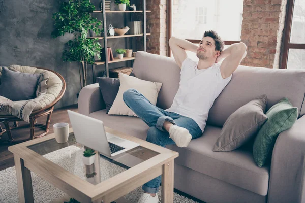 Портрет його привабливий м'язистий м'язистий хлопець, що сидить на паузі відпочинку дивана, працює дистанційно в сучасному індустріальному стилі лофт інтер'єру вітальні в приміщенні — стокове фото