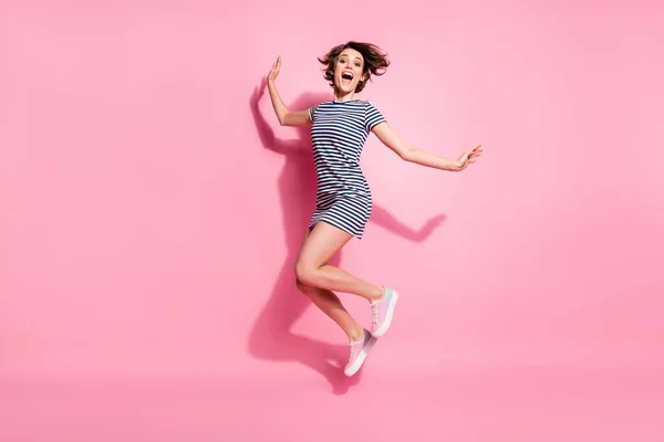 Full size profiel foto van funky kinderachtig dame mager vormen goed humeur springen hoog van vreugde dragen casual wit blauw zomer jurk schoenen geïsoleerd pastel roze kleur achtergrond — Stockfoto
