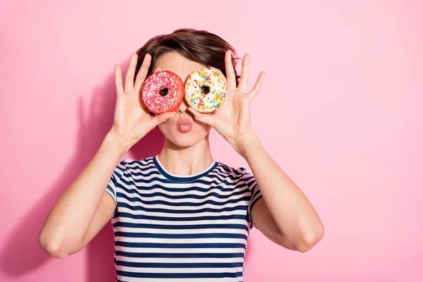 Close-up foto van aantrekkelijke grappige dame houd handen twee zoete gebakken donuts zoals specs in de buurt van ogen verzenden lucht kussen dragen casual wit blauw t-shirt geïsoleerde pastel roze kleur achtergrond — Stockfoto