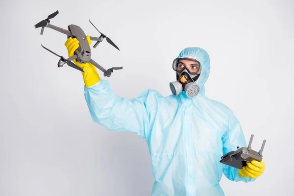 Portrait man hold joystick robot airplane drone imagine air fly video wear white suit hazmat yellow latex rubber gloves goggles glasses breathing mask isolated grey color background
