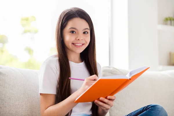 閉じる写真の小さなかわいい生徒の女の子の書き込みコピー本の宿題座ってソファホーム国内距離隔離ホーム勉強快適なリビングルーム屋内 — ストック写真