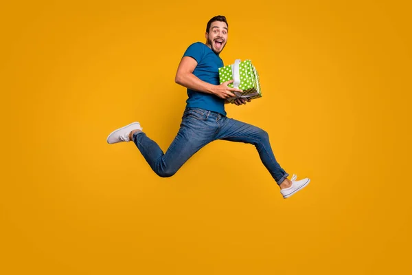 Повна довжина тіла погляд на його гарний привабливий божевільний веселий веселий хлопець стрибає тримаючи в руках подарункову коробку ізольовано на яскравому яскравому яскравому яскравому жовтому тлі — стокове фото