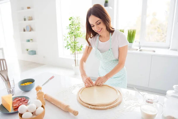 Retrato de positiva alegre dona de casa menina preparar pizza fazer crostas em madeira cortando bordo desgaste avental pontilhado na cozinha moderna branca — Fotografia de Stock