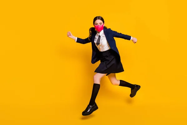 Foto lateral de perfil de cuerpo completo de estudiante de secundaria loca salto carrera copyspace desgaste chaqueta chaqueta negra falda calcetines largos máscara médica aislado sobre fondo de color amarillo —  Fotos de Stock