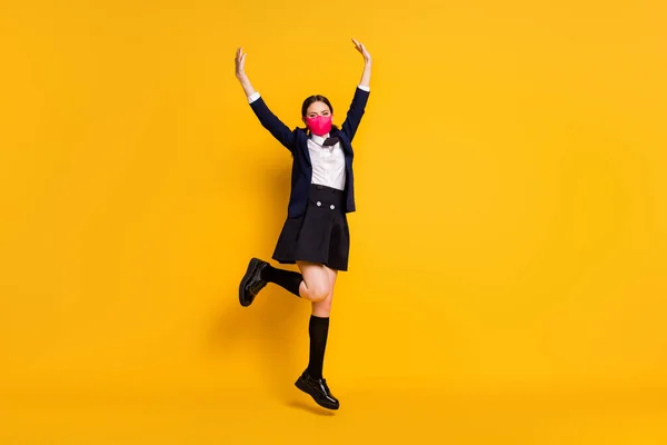 フルサイズの写真の高校生の女の子ジャンプ楽しむcovid-19隔離服黒ブレザージャケット長いソックススカート医学マスク絶縁上明るい輝き色背景 — ストック写真