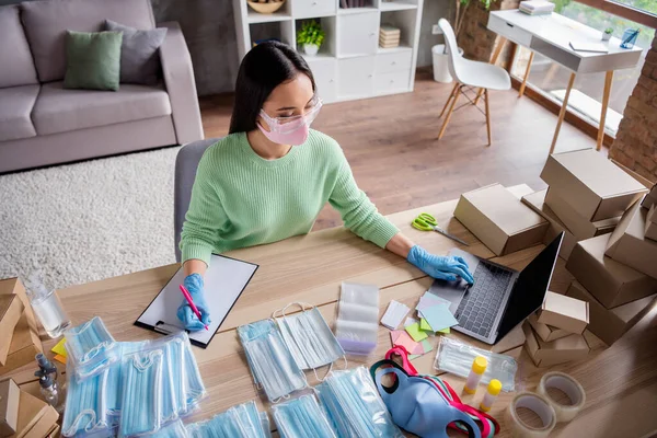 Foto van aziatische zakenvrouw organiseren lezen schrijven notebook orders manager gezichtsgriep maskers product internet service voorbereiding levering pakket veiligheid thuis kantoor quarantaine binnen — Stockfoto