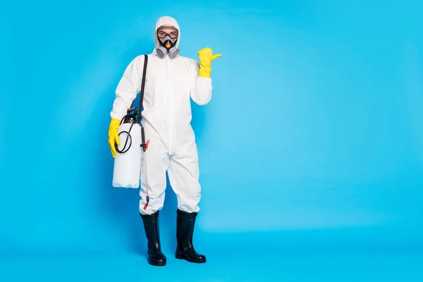 Full size photo medical worker in hazmat white protective suit latex yellow gloves breggles point thumb copyspace direct way dezinfekce ncov service isolated blue color background — Stock fotografie