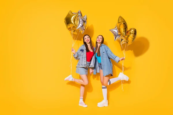 Full length body size view of nice attractive slender cheerful cheery girls holding in hands air balls dancing having fun isolated on bright vivid shine vibrant yellow color background — стоковое фото