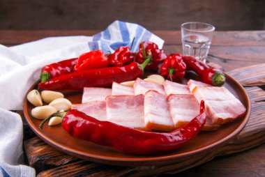 Domuz yağı - Ukrayna ulusal yemeği. Domuz pastırması, kırmızı biber ve ahşap arka planda seramik tabakta sarımsak. 