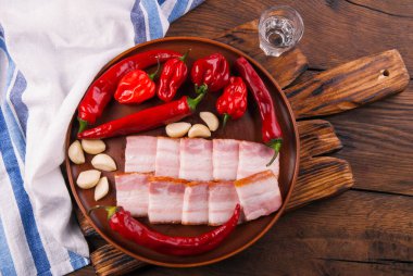 Domuz yağı - Ukrayna ulusal yemeği. Domuz pastırması, kırmızı biber ve ahşap arka planda seramik tabakta sarımsak. 