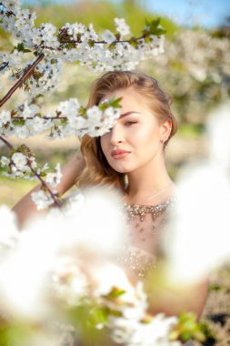 Bahar. Güzel bir kız bahçede çiçeklenme tree yakınındaki yakın çekim dikey portresi. Uzağa arıyorsunuz. Sanat. Kopya alanı 