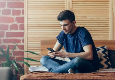 bir erkeğin ellerinin iç, arka görünümünde hipster el cep telefonu, telefon yatak odak el üzerinde oturan yazarak genç erkek öğrenci kullanarak meşgul akıllı telefon kullanarak yan görünümü vurdu. Kopya alanı