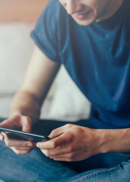 Clouse-up yan hipster el cep telefonu, telefon yatak odak el üzerinde oturan yazarak genç erkek öğrenci kullanarak meşgul iç, arka görünümünde akıllı telefon kullanarak bir adamın elleri görüntüsünü görüntüleyin. Kopya alanı