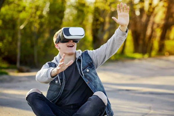 Vr ile yolda oturan genç sarışın adam gözlük ve eğlenin. Açık. Kopya alanı.