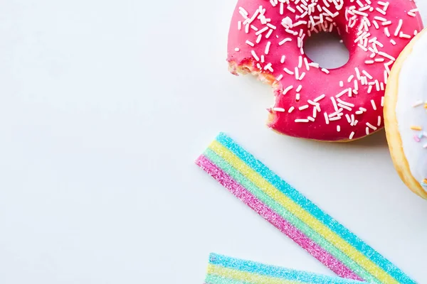 Yakın çekim ısırıldı pembe çörek ve jöle şekerler izole beyaz arka plan üzerinde. Kopya alanı.