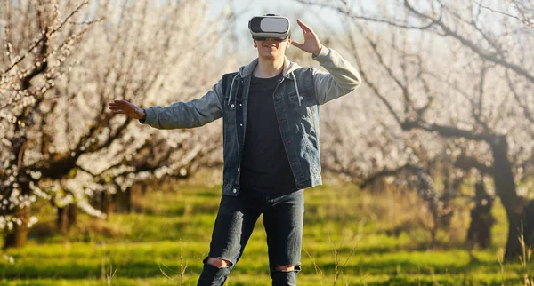 Sanal gerçeklik gözlük herif çekip genç çiçek açması Bahçe üzerinde gider. Açık.