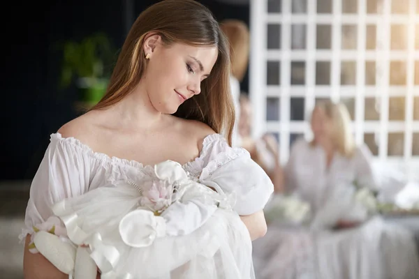 Beyaz elbiseli Holding tatlı bebek kız anne. Ailesi arka planı.