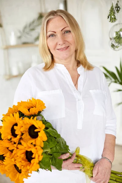 Kameraya, seyir çiçek tutan mutlu yaşlı kadın portresi gülümseyen