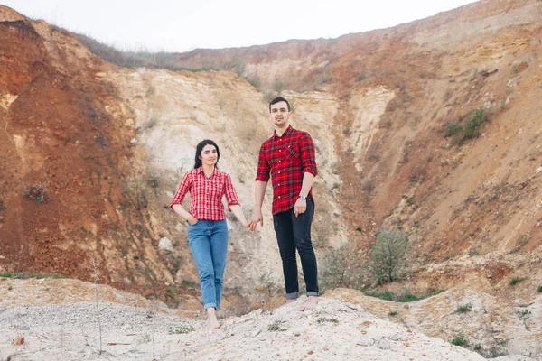 Encantador casal em camisas xadrez vermelho em pé no desfiladeiro de areia ou qua — Fotografia de Stock