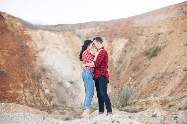 Encantador casal em camisas xadrez vermelho de pé e abraçar na areia c — Fotografia de Stock