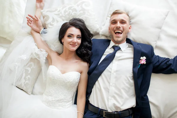 Portraite happy wedding couple have fun lying on white bed in th — Stock Photo, Image
