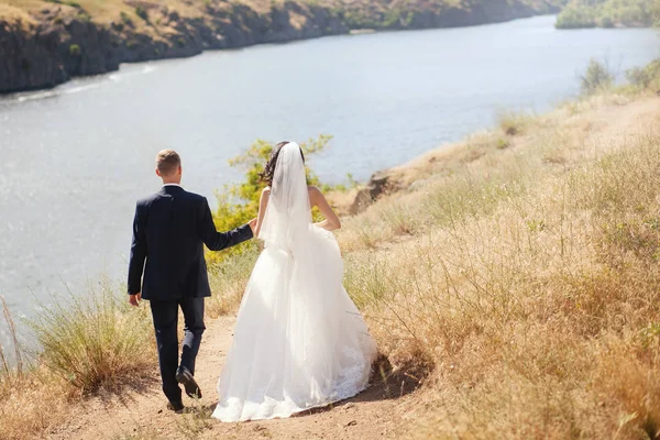 Honeymoon couple holding hands walking on perfect rivers beach. — Stock Photo, Image