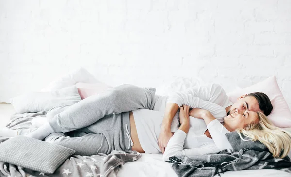 Genç çift rahatlatıcı, kucaklamak ve yatakta yatıyordu eğlenceli.