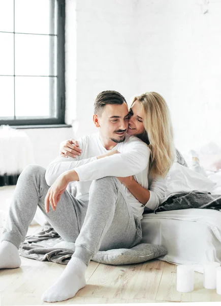 Genç çift kucaklayan yastık ile katta oturur.