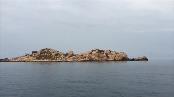 Остров на море в облачный день с серым небом и спокойной водой — стоковое видео