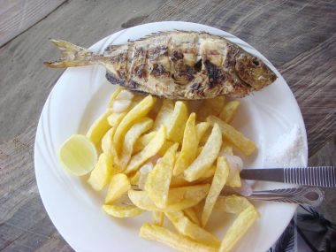 Beyaz çanak üzerinde kızarmış balık ve tuz ile Chipsy Samaki cips