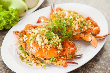 Beyaz çanak üzerinde soğan, marul ve otlar ile kızarmış Kırmızı yengeç