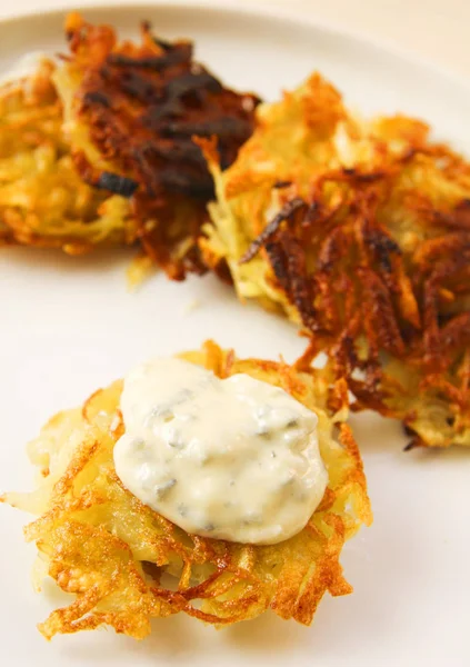 Potato pancakes with creamy sauce on white platter — Stock Photo, Image