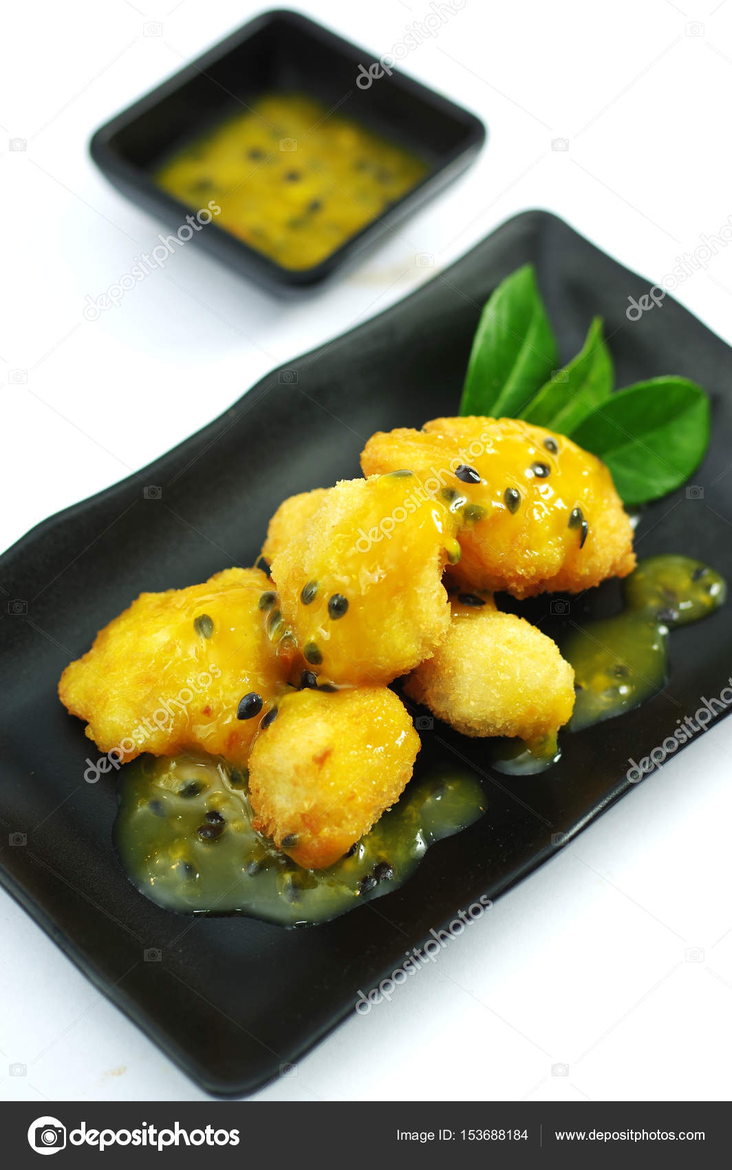 Chicken fried with passion fruit sauce on black platter — Stock Photo