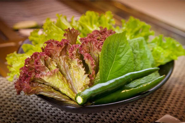 Pimienta verde fresca con lechuga en un tazón negro — Foto de Stock