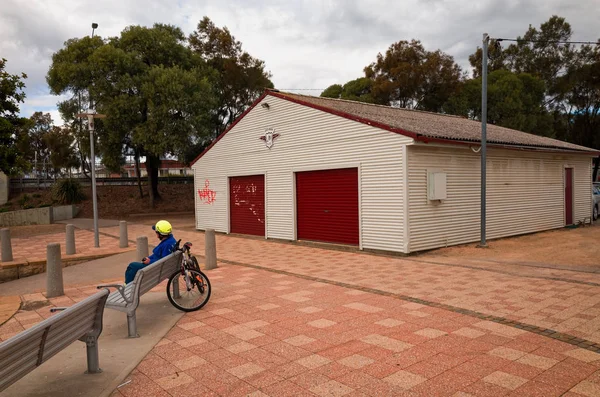 Adolescente en casco de bicicleta sentado en el banco del parque en Swansea — Foto de Stock