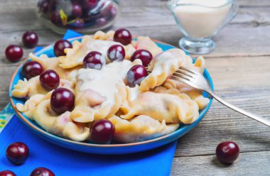 In blue ceramic dish, fruit and berry dumplings with cherries