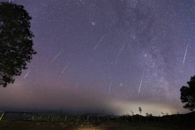Geminid Meteor yağmuru ve bir dağın üzerinden Samanyolu. Gece gökyüzünde Geminid Meteor