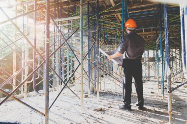 Engineer or foreman with blueprint in building construction site