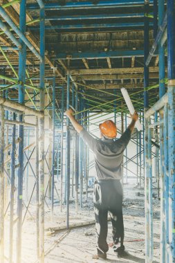 İnşaat alanının planına sahip mühendis ya da ustabaşı. İnşaat alanında başarılı olmak için ellerini kaldırdı..