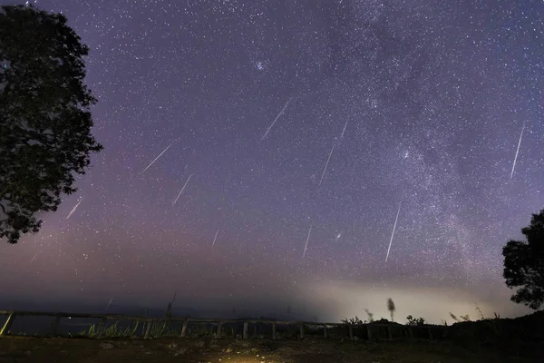 Geminid Meteor yağmuru ve bir dağın üzerinden Samanyolu. Gece gökyüzünde Geminid Meteor