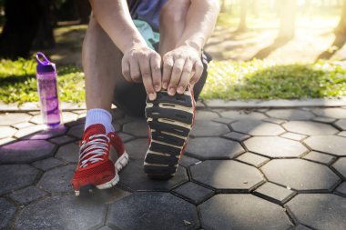 Asyalı sporcular parkta koşmadan önce bacaklarını esnetiyorlar. Kilo vermek ve sağlıklı olmak için yarışmak