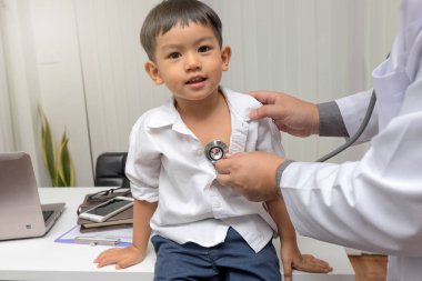Pediatrician is diagnosing little patient using a stethoscope
