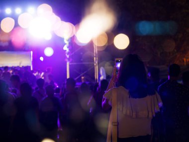 Audience take a photo on mobile phone at a free night concert music festival.