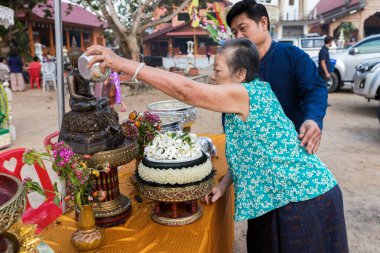 15 Nisan 2018 - Tayland, Chiang Mai: Taylandlı yaşlı kadın ve oğlu Tayland Songkran Festivali 'nde Buda heykelini yıkıyorlar.