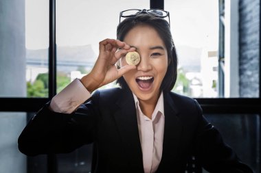 Elinde altın bir Bitcoin tutan komik bir iş kadını gözlerini kapatıyor.