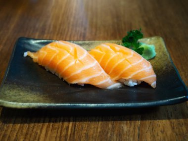 Siyah seramik diske somon balığı konmuş. Japon mutfağı..